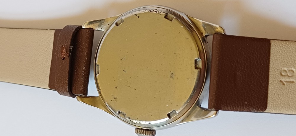 A vintage 1950s Omega wristwatch with a cream dial, gold hour markers, stainless steel case, and a smooth brown leather strap. View V