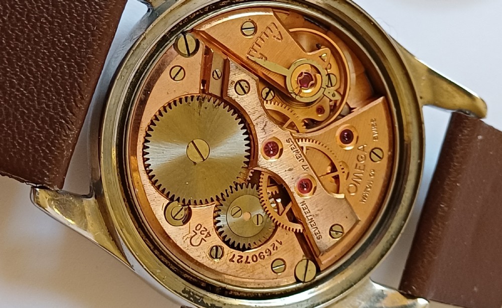 A vintage 1950s Omega wristwatch with a cream dial, gold hour markers, stainless steel case, and a smooth brown leather strap. View VIII