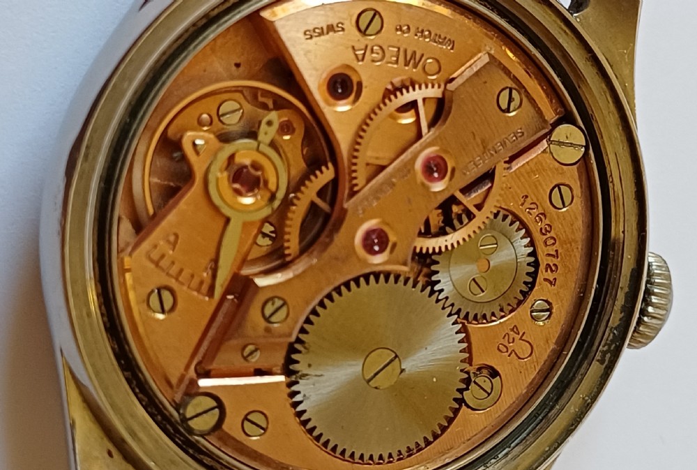A vintage 1950s Omega wristwatch with a cream dial, gold hour markers, stainless steel case, and a smooth brown leather strap. View IX