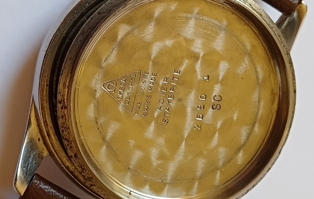 A vintage 1950s Omega wristwatch with a cream dial, gold hour markers, stainless steel case, and a smooth brown leather strap. View XI