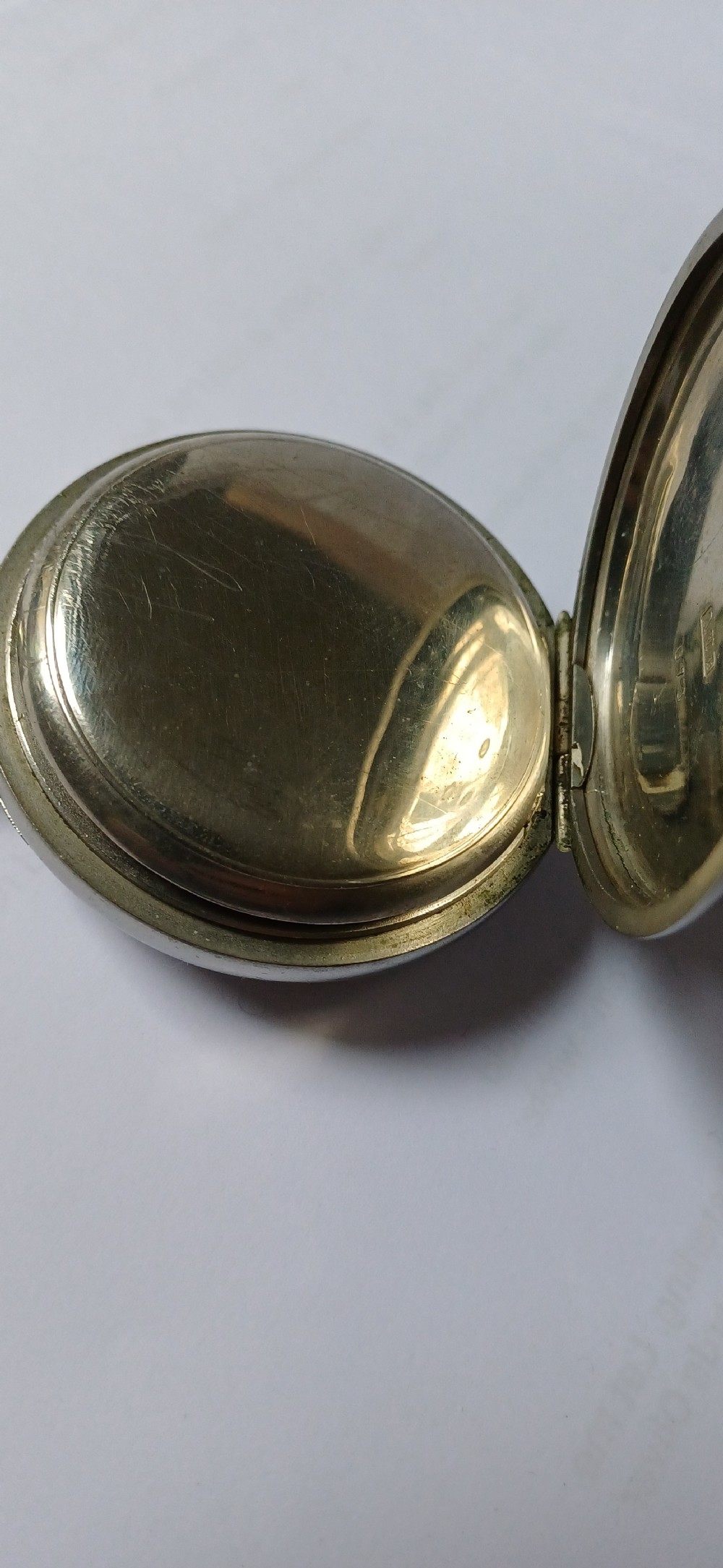 A black painted metal railway lantern with a top carrying handle alongside a silver-coloured pocket watch displaying Roman numerals. View XV