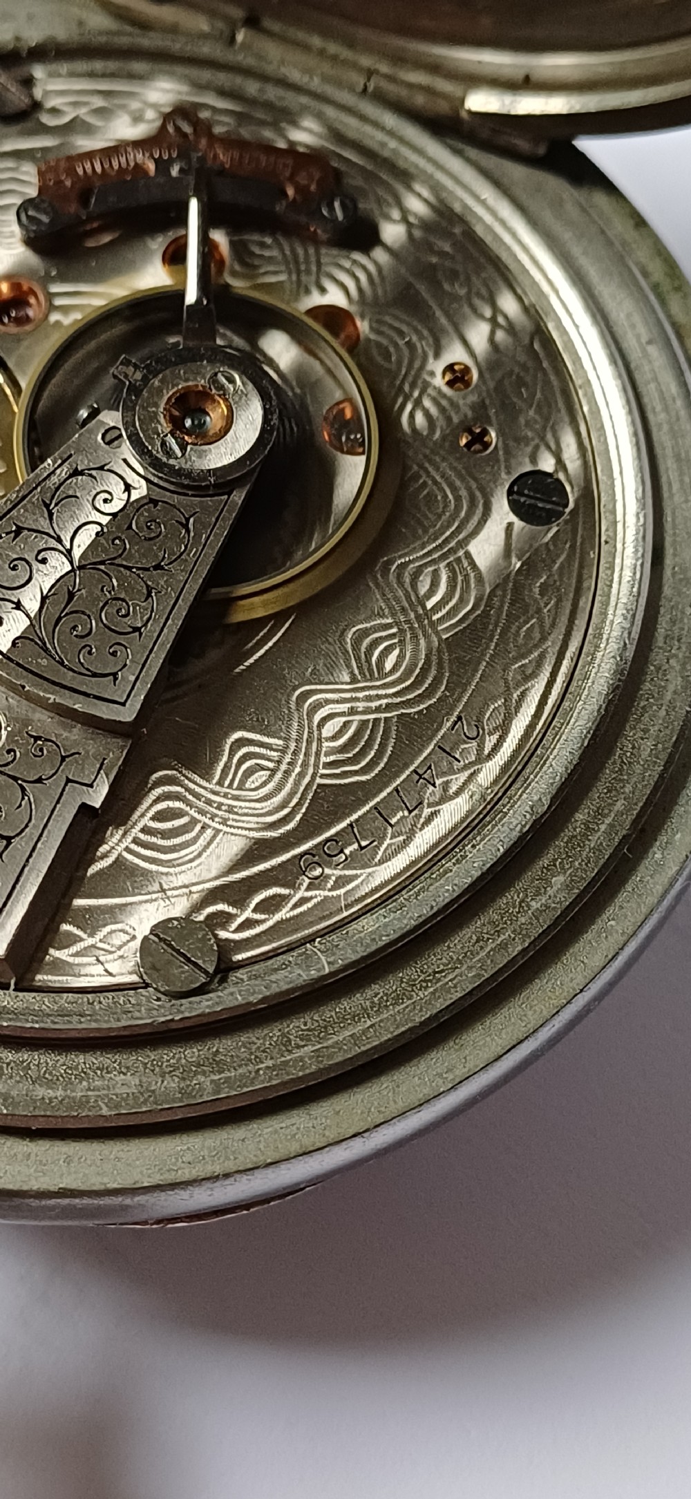 A black painted metal railway lantern with a top carrying handle alongside a silver-coloured pocket watch displaying Roman numerals. View XVIII