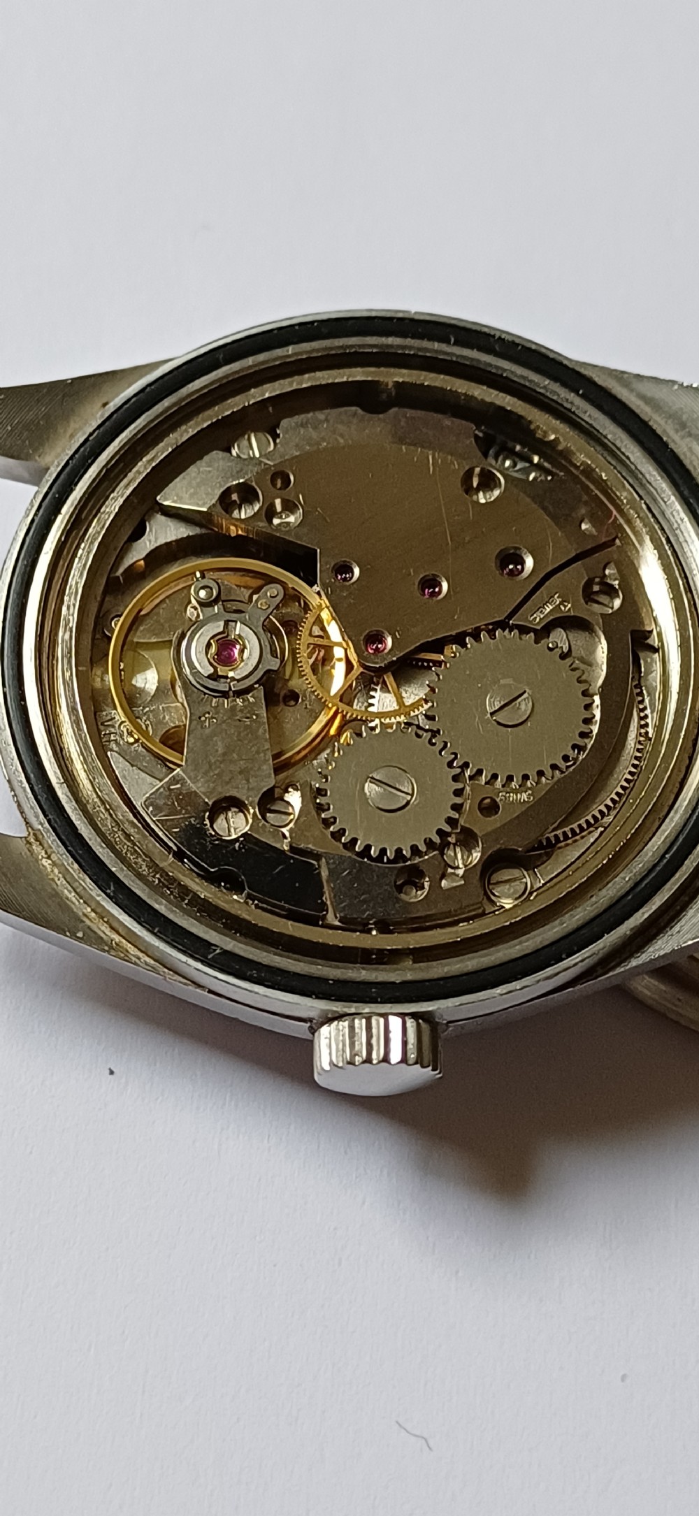 A vintage mid-century military wristwatch featuring a round steel case, a black dial with luminous Arabic numerals, outer minute markings, and luminescent hands. View XII