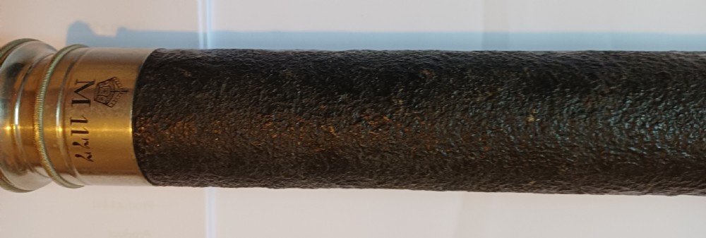 An antique brass single-draw naval telescope wrapped in textured black leather with official markings engraved near the eyepiece. View III