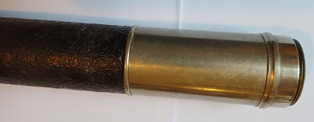 An antique brass single-draw naval telescope wrapped in textured black leather with official markings engraved near the eyepiece. View VII