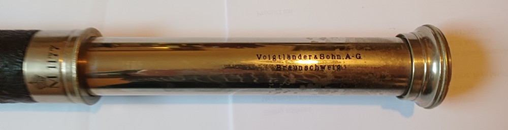 An antique brass single-draw naval telescope wrapped in textured black leather with official markings engraved near the eyepiece. View XI
