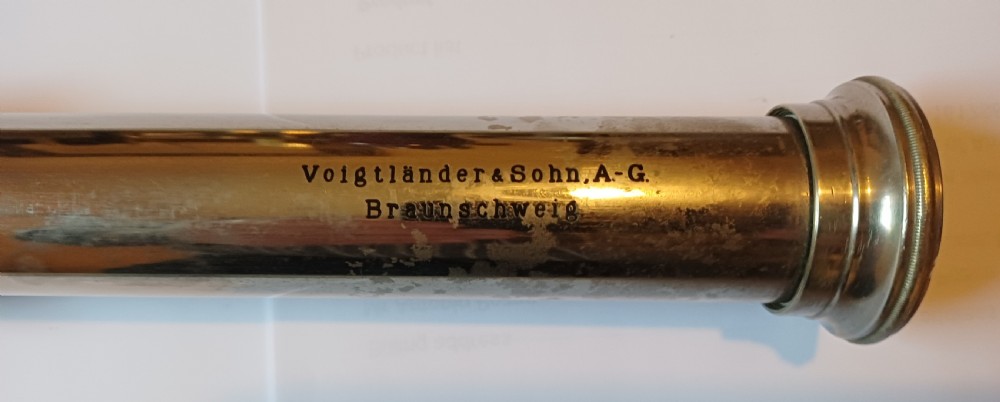 An antique brass single-draw naval telescope wrapped in textured black leather with official markings engraved near the eyepiece. View XII