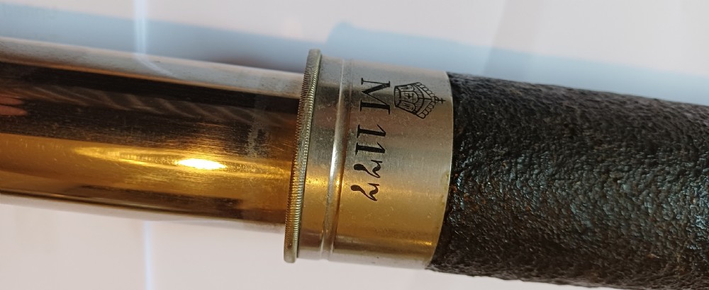 An antique brass single-draw naval telescope wrapped in textured black leather with official markings engraved near the eyepiece. View XV