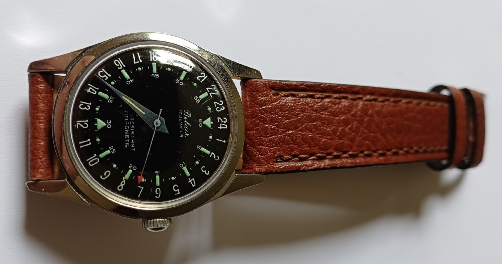 A 1960s Belair wristwatch featuring a black 24-hour dial with luminous hour markers, arrow hands, and a brown leather strap. View III