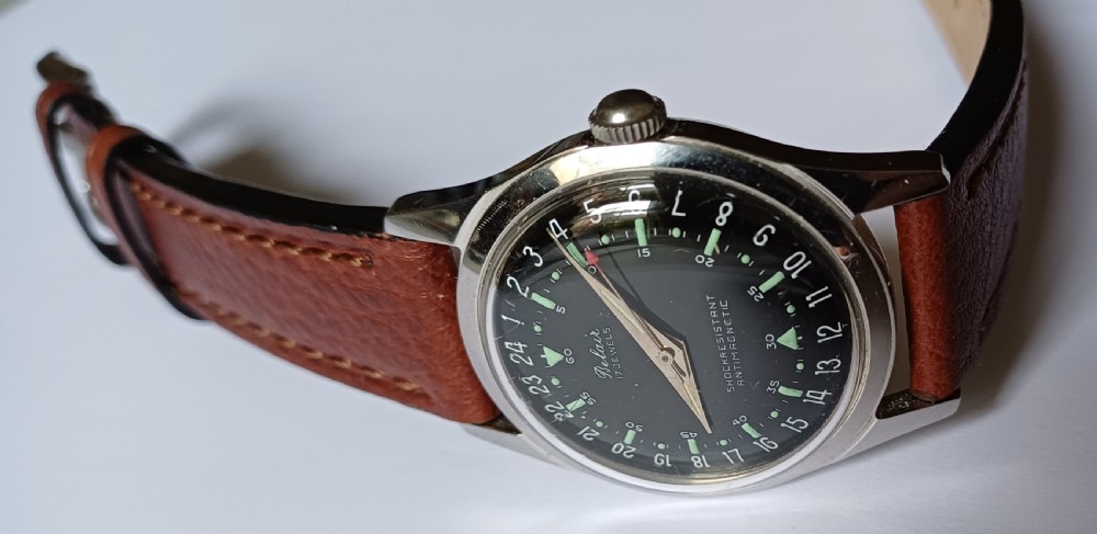 A 1960s Belair wristwatch featuring a black 24-hour dial with luminous hour markers, arrow hands, and a brown leather strap. View VI