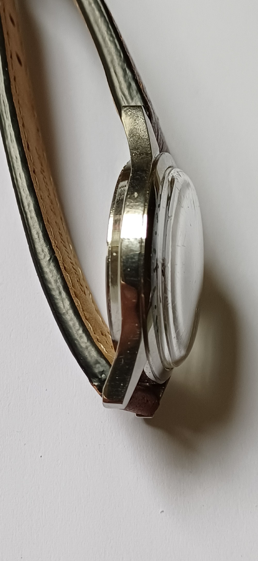 A 1960s Belair wristwatch featuring a black 24-hour dial with luminous hour markers, arrow hands, and a brown leather strap. View VII