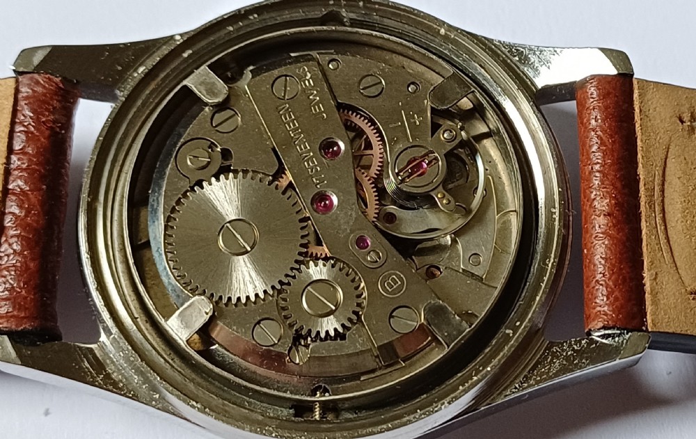 A 1960s Belair wristwatch featuring a black 24-hour dial with luminous hour markers, arrow hands, and a brown leather strap. View XIII