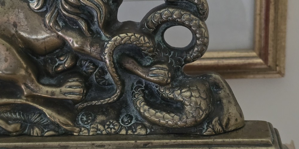 A heavy cast brass Victorian doorstop featuring a sculptural lion wrestling a coiled serpent atop a moulded plinth base. View III