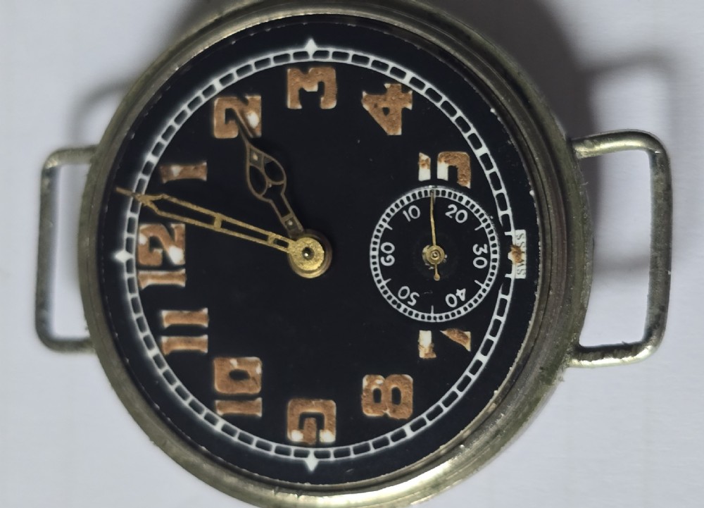 An antique military trench watch featuring a black dial with aged luminous numbers, cathedral hands, a small sub-seconds dial, wire lugs, and a coin-edge bezel. View VIII