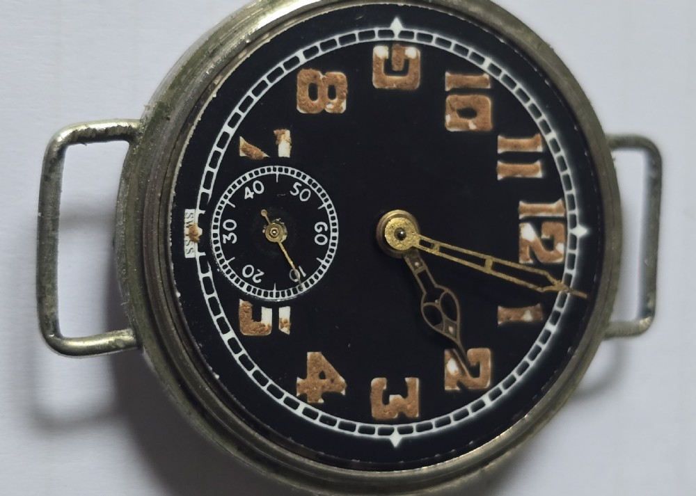 An antique military trench watch featuring a black dial with aged luminous numbers, cathedral hands, a small sub-seconds dial, wire lugs, and a coin-edge bezel. View XI