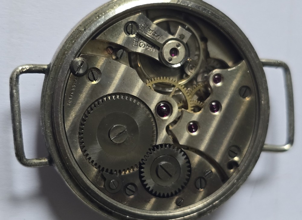 An antique military trench watch featuring a black dial with aged luminous numbers, cathedral hands, a small sub-seconds dial, wire lugs, and a coin-edge bezel. View XVII
