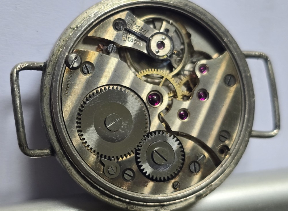 An antique military trench watch featuring a black dial with aged luminous numbers, cathedral hands, a small sub-seconds dial, wire lugs, and a coin-edge bezel. View XIX