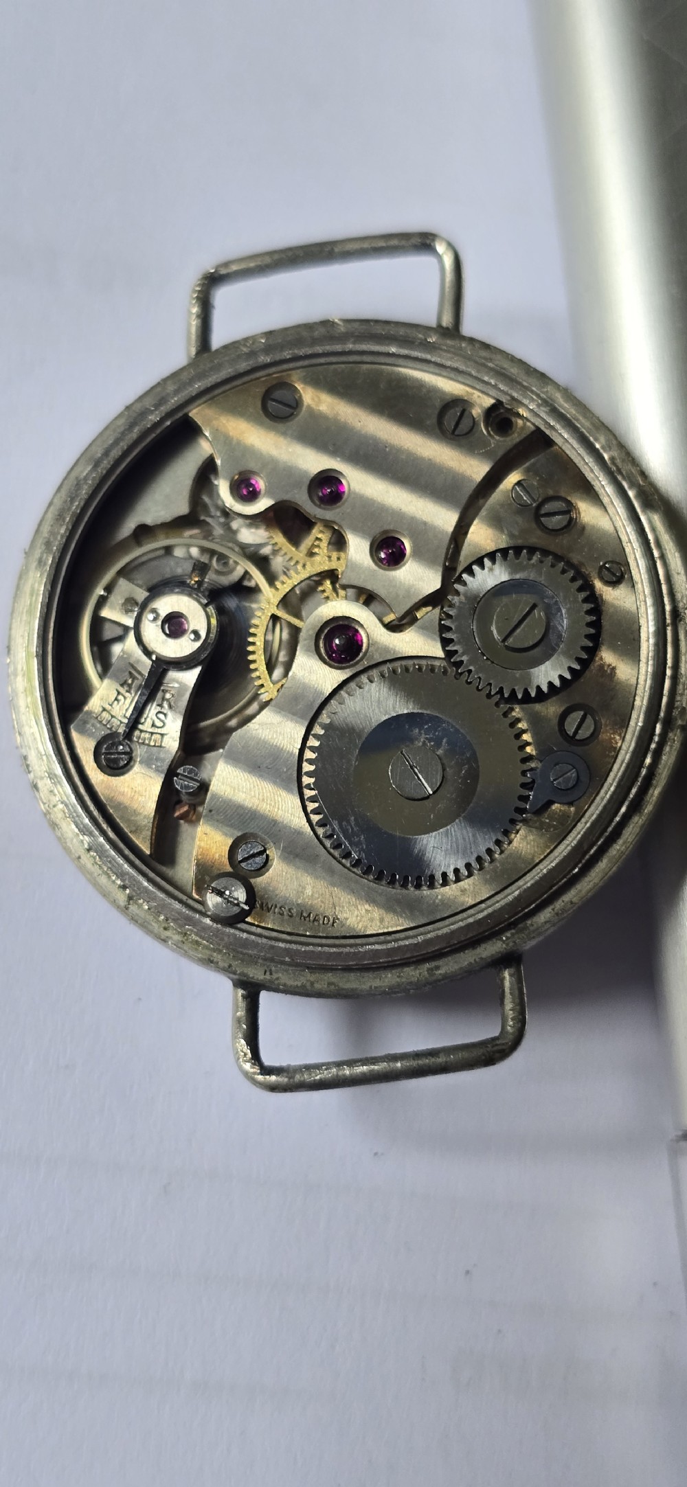 An antique military trench watch featuring a black dial with aged luminous numbers, cathedral hands, a small sub-seconds dial, wire lugs, and a coin-edge bezel. View XX
