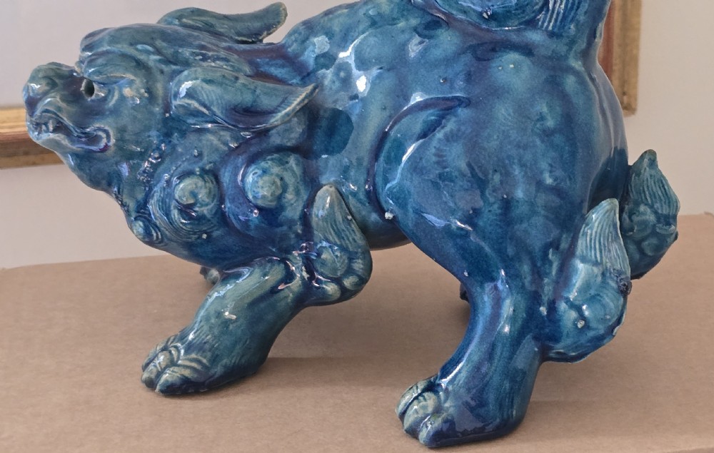A Japanese glazed ceramic shishi guardian lion rendered in a rich turquoise blue glaze with a raised curling tail. View XII