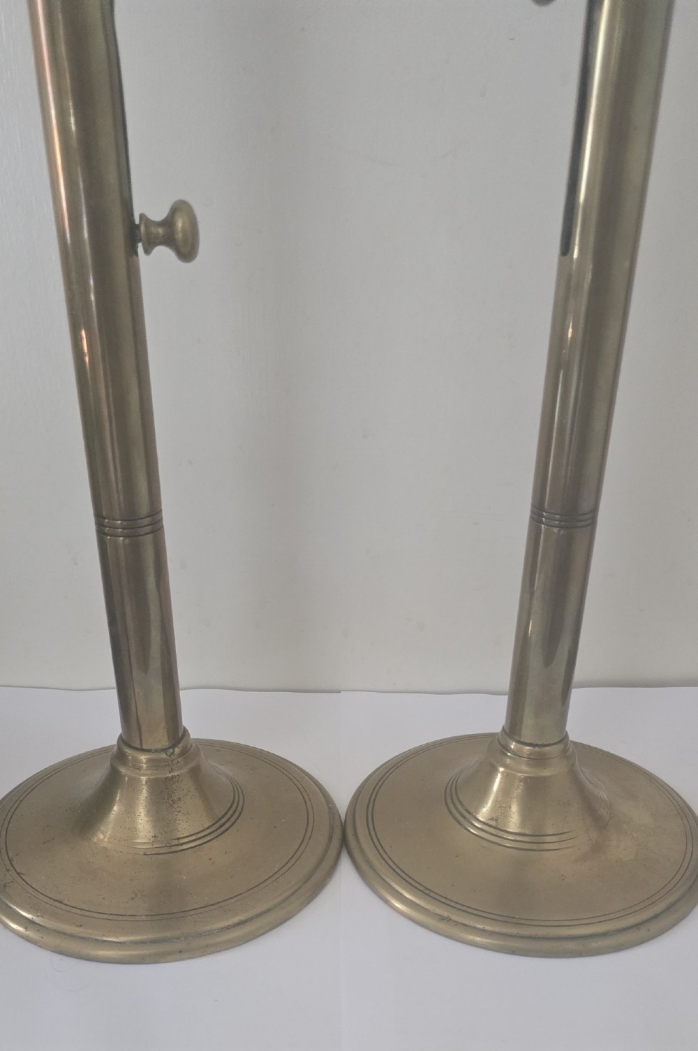 A pair of tall Georgian brass candlesticks featuring circular stepped bases, cylindrical stems, top wax pans, and side ejector push-up knobs. View II