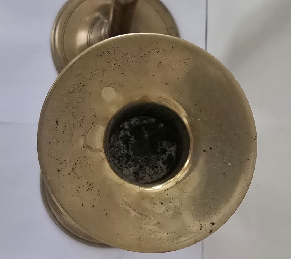 A pair of tall Georgian brass candlesticks featuring circular stepped bases, cylindrical stems, top wax pans, and side ejector push-up knobs. View IV