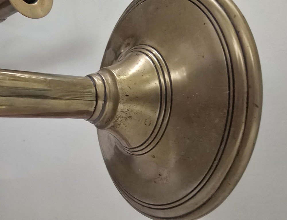 A pair of tall Georgian brass candlesticks featuring circular stepped bases, cylindrical stems, top wax pans, and side ejector push-up knobs. View V