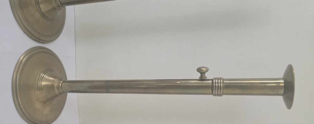 A pair of tall Georgian brass candlesticks featuring circular stepped bases, cylindrical stems, top wax pans, and side ejector push-up knobs. View XII