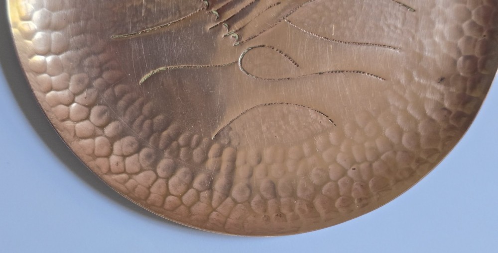 A circular hand-hammered copper visiting card tray featuring a central repousse fish motif surrounded by chased water lines and a spot-hammered rim. View VII