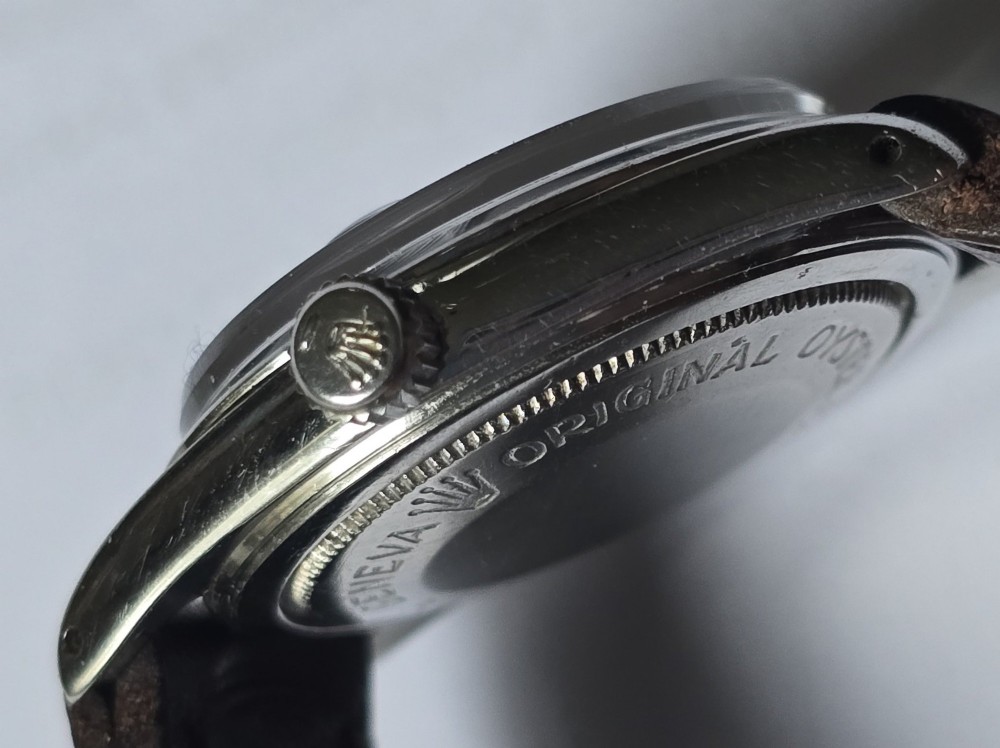 A vintage Tudor Prince Oysterdate wristwatch with a stainless steel case, a black dial featuring baton hour markers, a date aperture at three oclock, and a dark brown leather strap. View VI