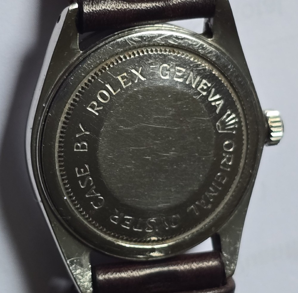 A vintage Tudor Prince Oysterdate wristwatch with a stainless steel case, a black dial featuring baton hour markers, a date aperture at three oclock, and a dark brown leather strap. View IX