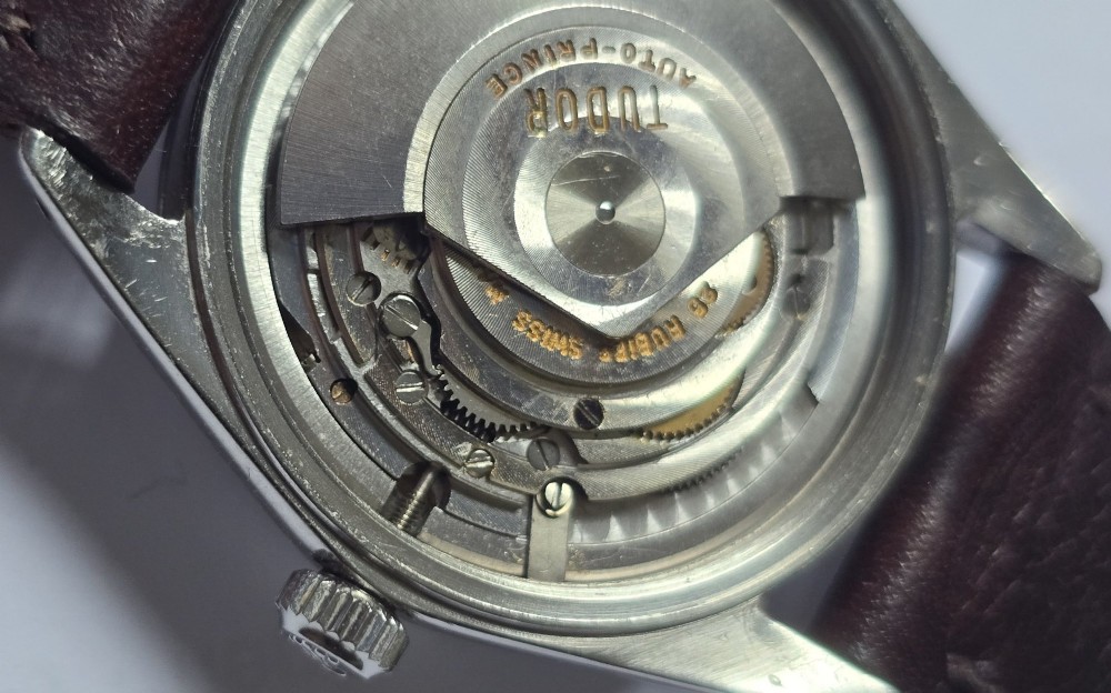 A vintage Tudor Prince Oysterdate wristwatch with a stainless steel case, a black dial featuring baton hour markers, a date aperture at three oclock, and a dark brown leather strap. View XI