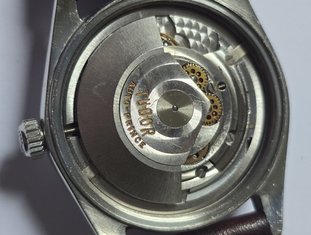 A vintage Tudor Prince Oysterdate wristwatch with a stainless steel case, a black dial featuring baton hour markers, a date aperture at three oclock, and a dark brown leather strap. View XIV