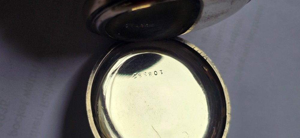 An open-face military pocket watch chronograph featuring a white enamel dial with black Arabic numerals, dual sub-dials, and French military markings enclosed in a round silver case. View X