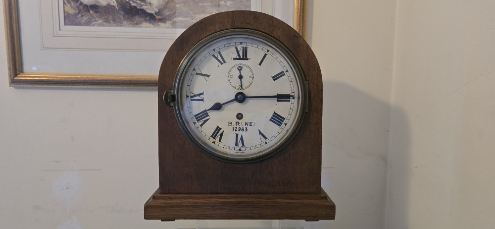 An arched wooden mantel clock featuring a white dial with Roman numerals, a brass bezel, and British Rail markings.