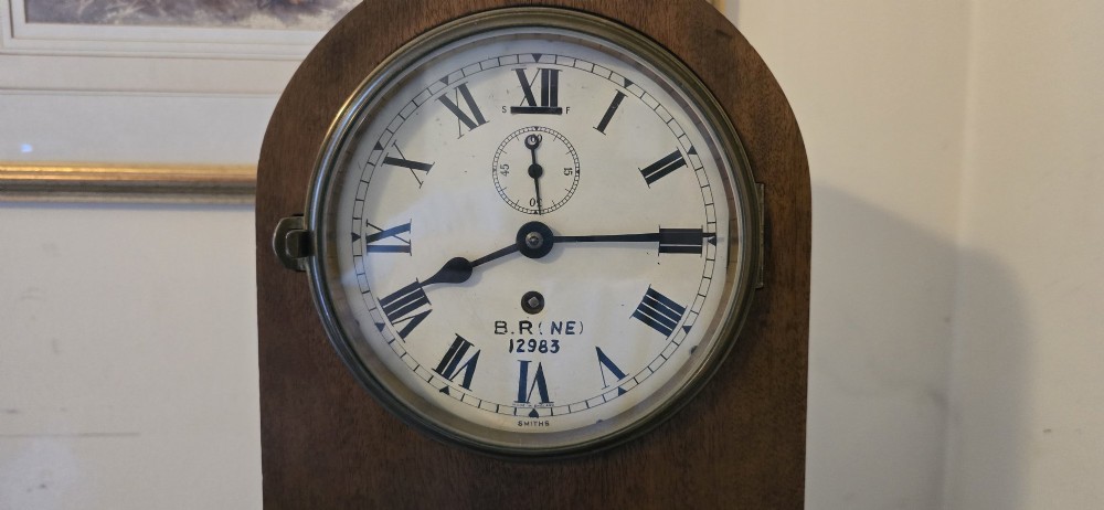An arched wooden mantel clock featuring a white dial with Roman numerals, a brass bezel, and British Rail markings. View II