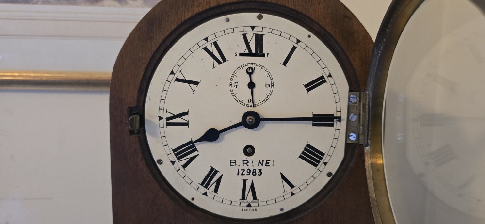 An arched wooden mantel clock featuring a white dial with Roman numerals, a brass bezel, and British Rail markings. View III