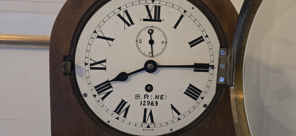 An arched wooden mantel clock featuring a white dial with Roman numerals, a brass bezel, and British Rail markings. View IV