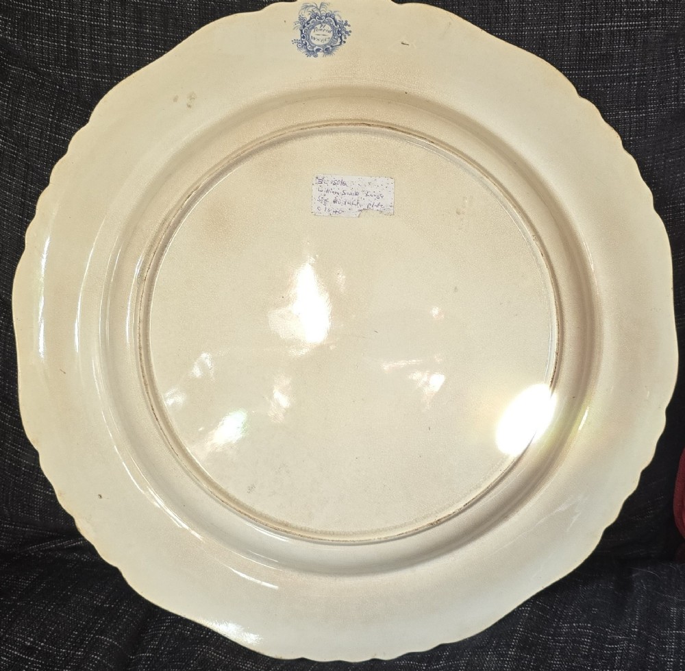 An antique circular earthenware plate featuring a blue transfer-printed central scene of Hannibal with an elephant and figures in a mountainous landscape, surrounded by an ornate scalloped floral border. View IX