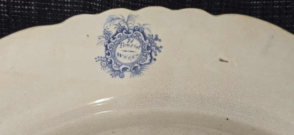 An antique circular earthenware plate featuring a blue transfer-printed central scene of Hannibal with an elephant and figures in a mountainous landscape, surrounded by an ornate scalloped floral border. View XI
