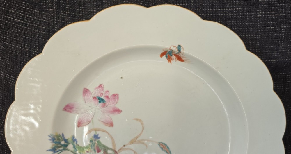 An antique circular off-white porcelain dish with a scalloped rim, hand-painted with pink lotus blossoms, foliage, a crane, and a waterfowl. View V