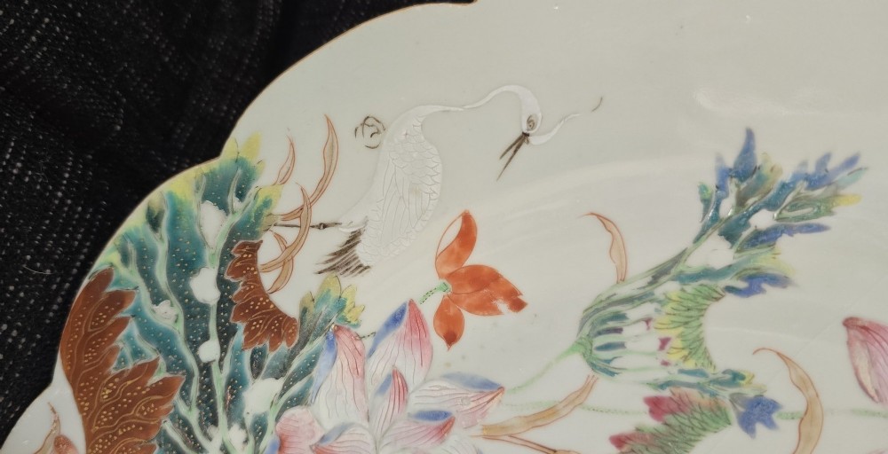 An antique circular off-white porcelain dish with a scalloped rim, hand-painted with pink lotus blossoms, foliage, a crane, and a waterfowl. View VI