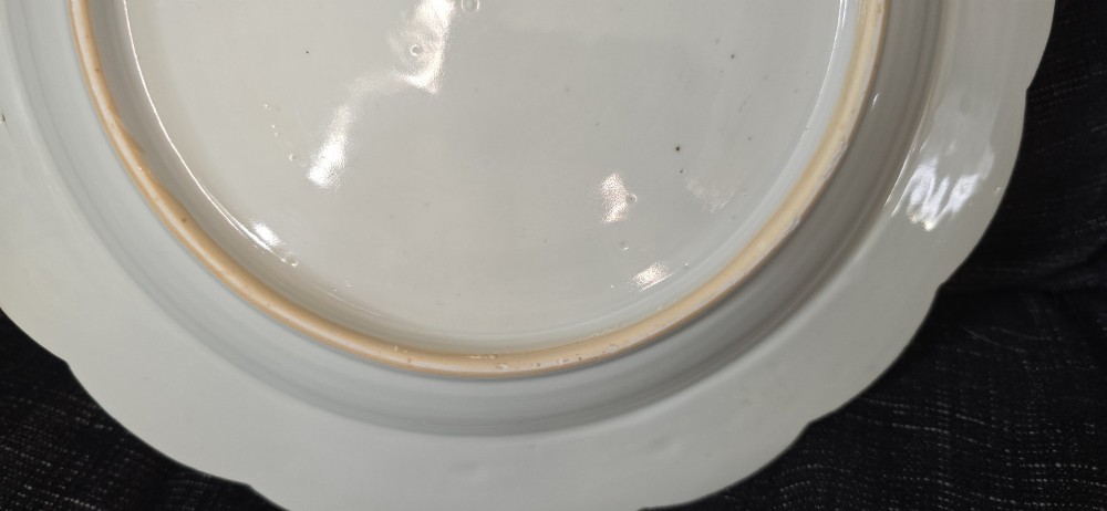 An antique circular off-white porcelain dish with a scalloped rim, hand-painted with pink lotus blossoms, foliage, a crane, and a waterfowl. View X