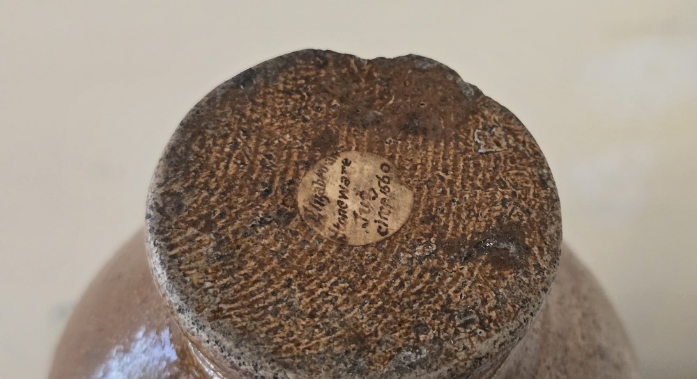 A 17th-century dark brown salt-glazed stoneware bottle featuring a bulbous body, narrow neck, turned base, and a single loop handle. View XIII