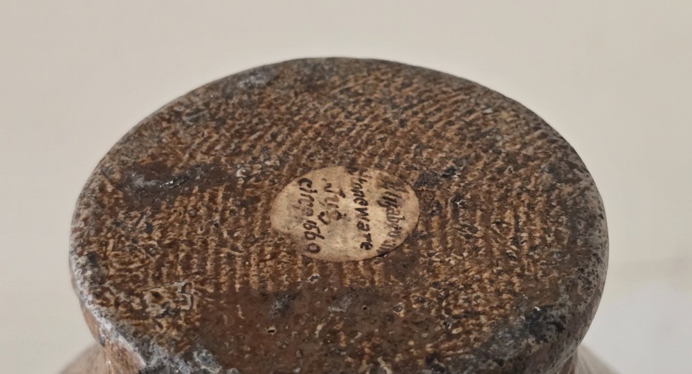 A 17th-century dark brown salt-glazed stoneware bottle featuring a bulbous body, narrow neck, turned base, and a single loop handle. View XIV