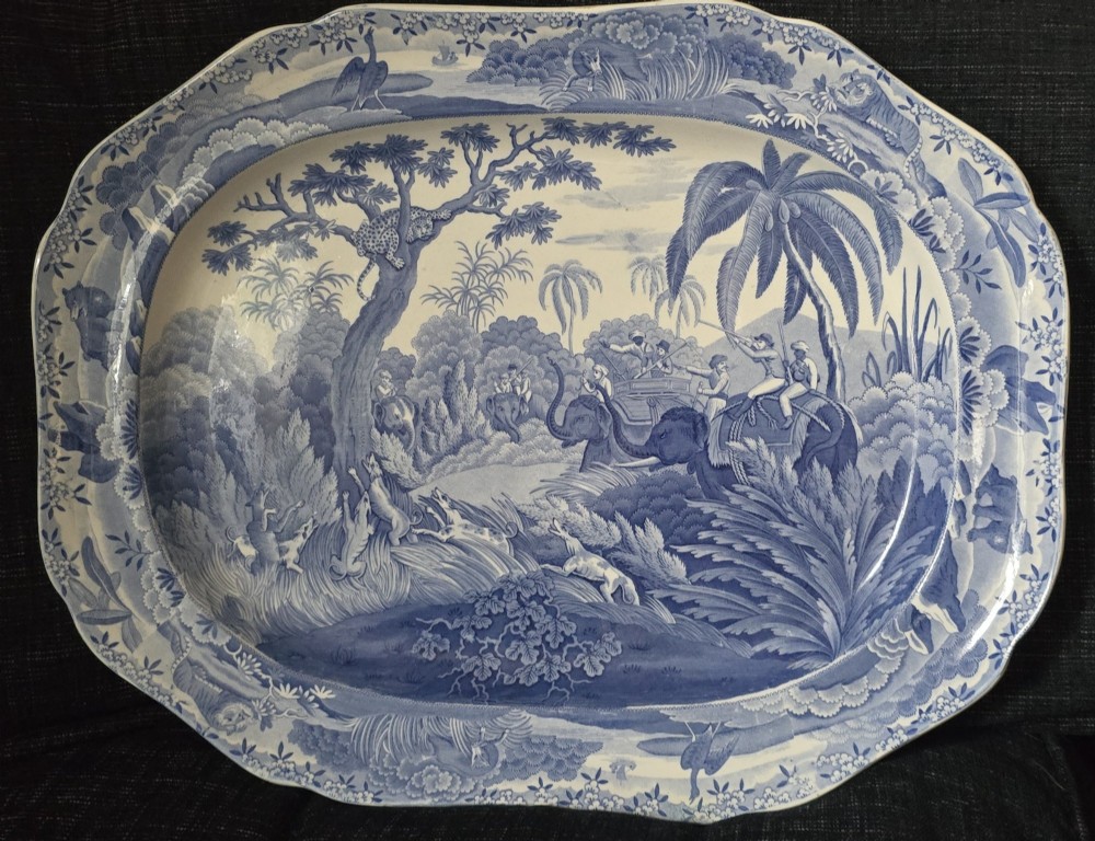 An oval blue and white underglaze transfer-printed earthenware meat platter depicting a landscape with hunters on elephants and hounds pursuing a leopard.