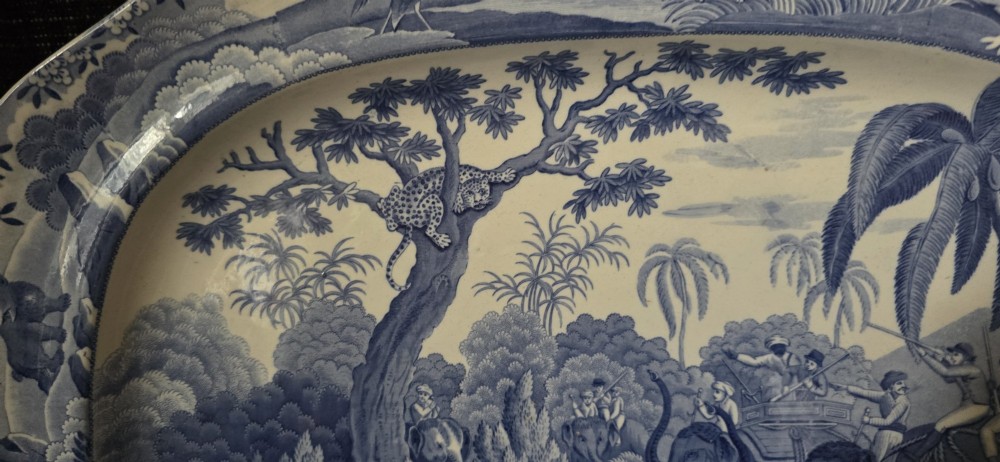 An oval blue and white underglaze transfer-printed earthenware meat platter depicting a landscape with hunters on elephants and hounds pursuing a leopard. View VI