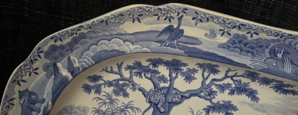 An oval blue and white underglaze transfer-printed earthenware meat platter depicting a landscape with hunters on elephants and hounds pursuing a leopard. View XII