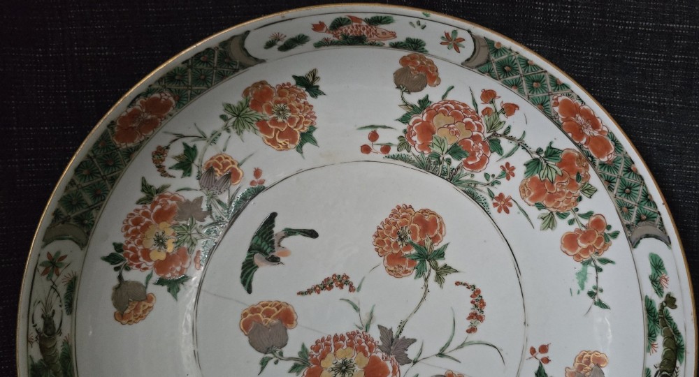 A circular Chinese famille verte porcelain dish featuring hand-painted peony blossoms, foliage, a bird in flight, and a decorative patterned border. View II