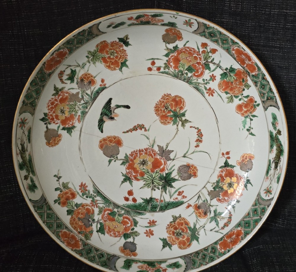 A circular Chinese famille verte porcelain dish featuring hand-painted peony blossoms, foliage, a bird in flight, and a decorative patterned border. View III