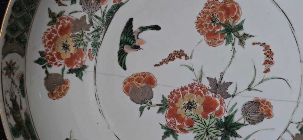 A circular Chinese famille verte porcelain dish featuring hand-painted peony blossoms, foliage, a bird in flight, and a decorative patterned border. View VI